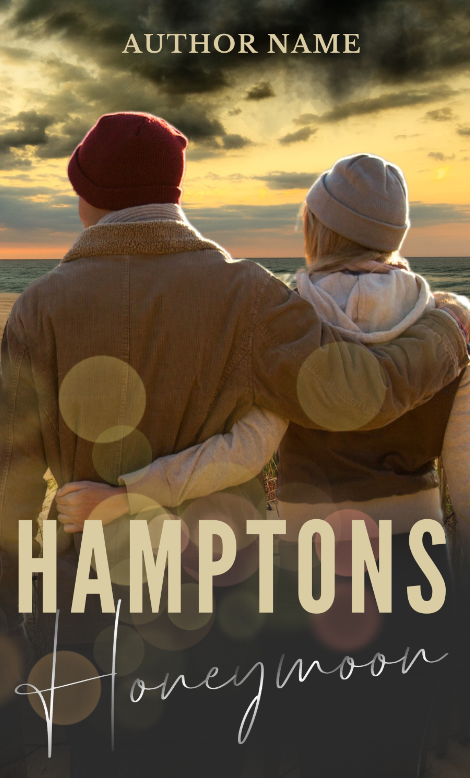 A romantic book cover titled "Hamptons Honeymoon: Ready Made Book Cover" features a couple from behind, wearing jackets and beanies, embracing while gazing at the ocean during a sunset. The author's name is at the top, and artistic light flares adorn the image. BookSelf Book Cover Design & Premade Book Covers